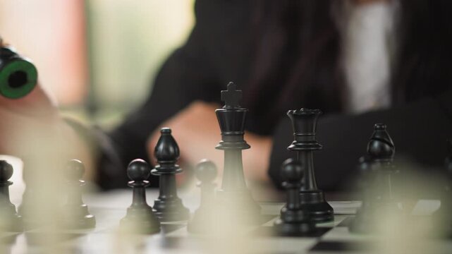 Close up of woman playing chess moving black pieces on board. focus remains tight throughout highlighting detailed textures and positions of pawns while capturing deliberate hand movements
