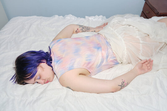 Stylish non-binary person resting on a white bed