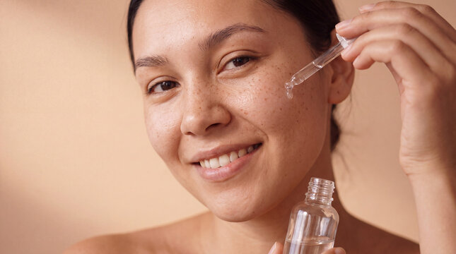 A young mixed-race woman holds an essence bottle with a soft smile for a beauty content post.