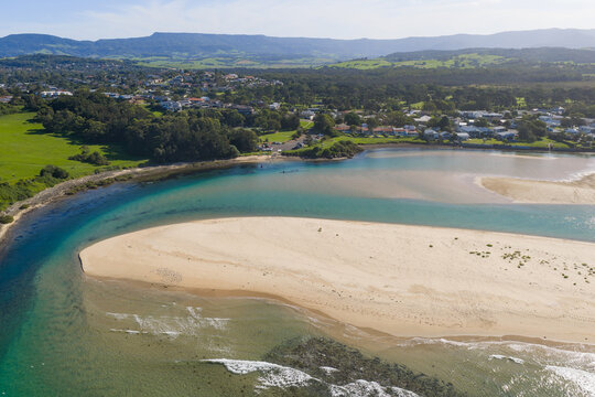 A coastal river rounding a sandy beach and flowing out to sea