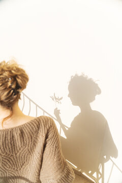 Woman and her shadow holding olive twig