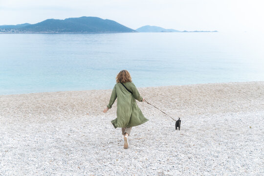 Woman walking cat on beach