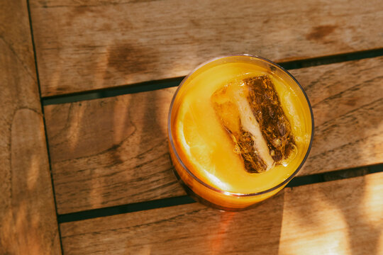 Fresh Beverage With Ice on Wooden Table in Sunny Setting