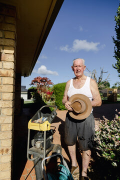 Portrait of active senior man beside pressure washer at home