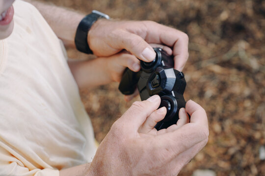 The Hands Of A Man And A Child With A Remote Control For A Toy Car