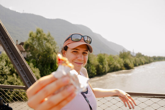 Woman offering snack on bridge during cycling trip in South Tyrol