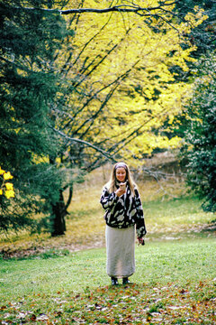 A woman looking at her cellphone in the middle of a forest