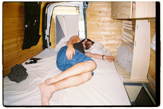 Man sleeping Inside a camper Van on a Bed