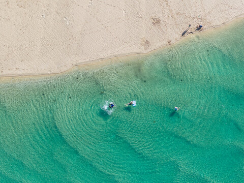 People swimming in turquoise water off a white sand beach
