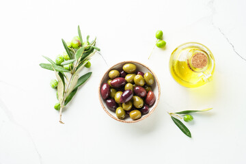 Obraz premium Olives in wooden bowl and fresh olive tree branch at white background.