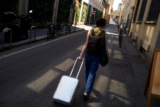 Walking Down a City Street With a Suitcase in Hand