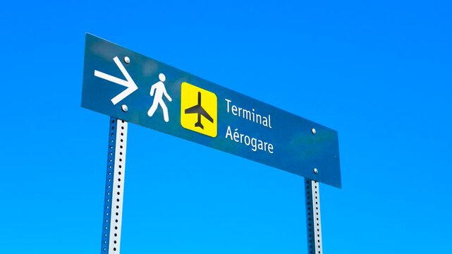 Bilingual Airport Directional Sign for Terminal and Aerogare Against Blue Sky
