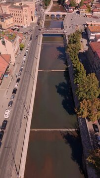 Aerial Top Down Drone View Moving Upstream Along Miljacka River Towards Vijecnica City Hall