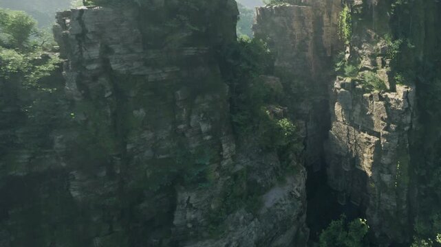 Several rocky cliffs rise high with patches of green plants covering the surfaces. The sun shines bright, creating shadows and highlights on the rocks.