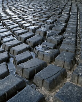 Rubber texture with a deep tread pattern featuring water droplets on a dark vulcanised surface for industrial and automotive backgrounds