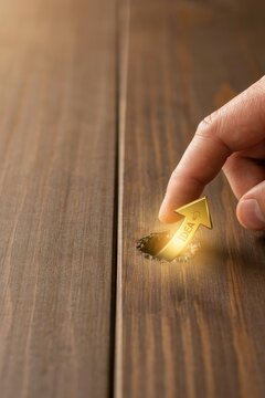 Hand lifting glowing gold arrow with idea word from wooden crack