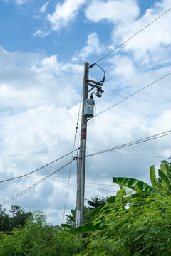 Poteau &eacute;lectrique avec transformateur et c&acirc;bles dans un paysage tropical