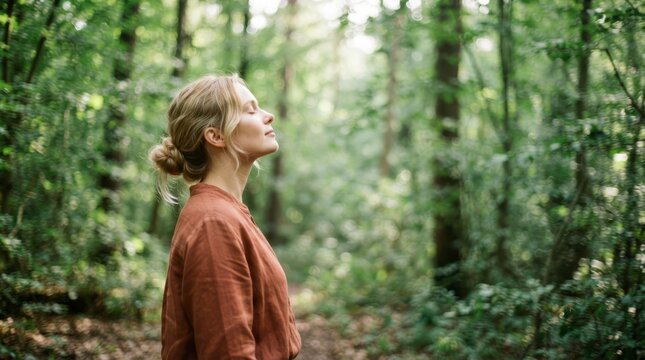 Woman with eyes closed breathing fresh air in a lush green forest