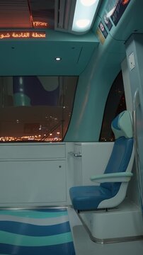 Sobha Realty metro carriage moves through Dubai at night, while a next station display glows above an empty blue seat