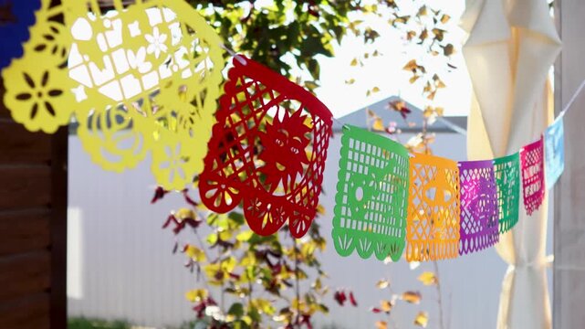 Outdoor Day of the Dead papel picado banners fluttering in a festive garden scene