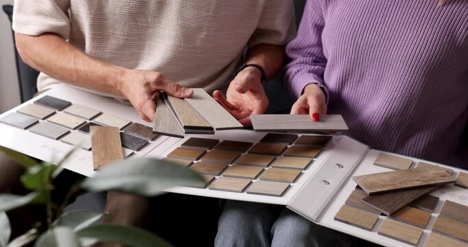 Couple choosing flooring and furniture materials from wood samples for home renovation. Interior design, house improvement