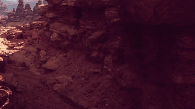 Visitors explore unique rock formations in a desert area during the day. The sun casts shadows on the ground, highlighting the texture of the rocks. The scene shows a natural landscape.