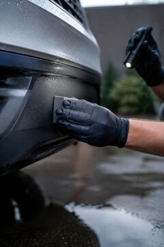 Detailer applying plastic trim restorer to car bumper