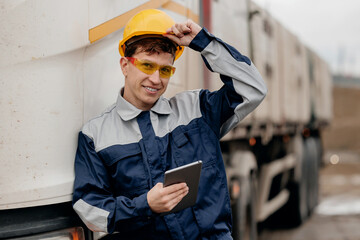 Portrait Smiling construction worker in safety helmet holding tablet by truck at sand quarry for industrial mining © Parilov