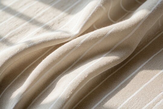 Textured light beige linen fabric with subtle pinstripes and soft folds. Natural material surface with horizontal shadows. Clean backdrop for design.