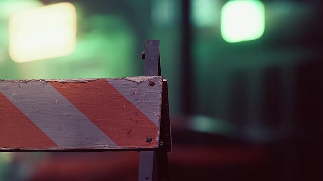 A weathered sign with bold orange and white stripes announces caution. It looms quietly in the dim light, indicating road work nearby, as the city moves serenely around it.
