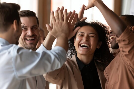Diverse business team celebrating success by giving high fives in modern office environment