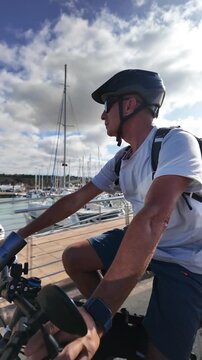 Healthy active man riding an electric bicycle along a marina on a sunny day, showcasing a sustainable lifestyle, freedom, and mental well-being while enjoying the outdoors
