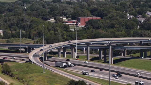 Aerial of interstate 470 interchange over forested suburban area in Kansas City Missouri with active traffic on the overpass and multilevel roads