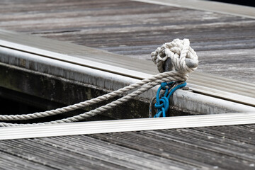 Mooring ropes tied around dock cleat on weathered wooden marina pontoon © Jane Allan