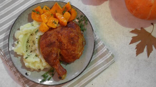 Roasted chicken quarter with glazed pumpkin, herbs and mashed potato, top view. Portion of festive autumn meal for Thanksgiving. Healthy seasonal food.
