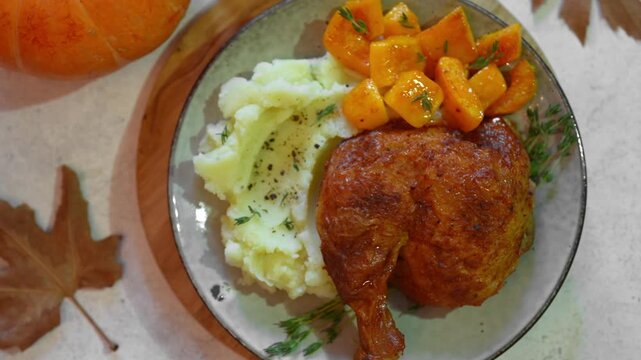 Roasted chicken quarter with glazed pumpkin, herbs and mashed potato, top view. Portion of festive autumn meal for Thanksgiving. Healthy seasonal food.