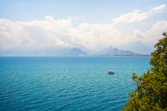 Beautiful blue sea and mountains in Antalya, Turkey. Tourist boat sailing near the coast. Famous travel destination
