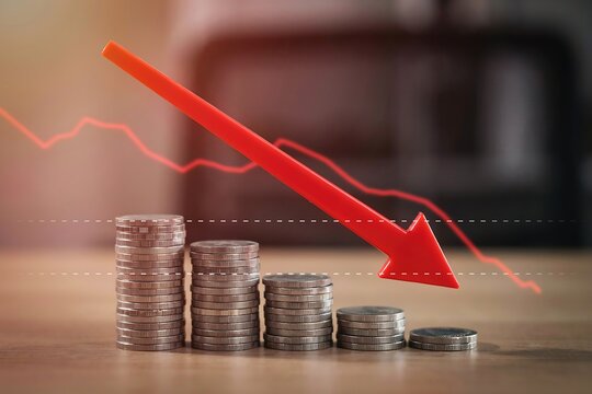 Stacks of coins with a red downward arrow showing financial loss and economic recession trend