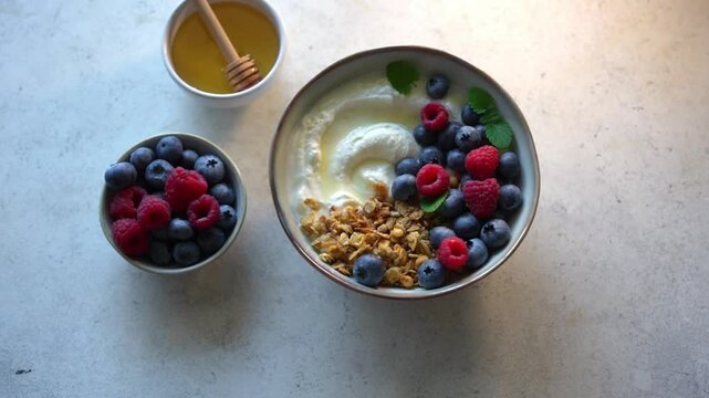Delicious bowl of greek yogurt topped with granola and fresh berries for healthy breakfast. Granola bowl with blueberries and raspberries close up.