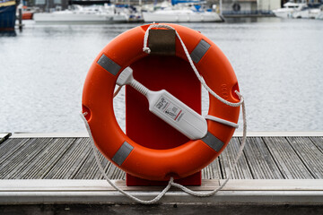 Orange lifebuoy with safety light and rope on marina pontoon for emergency water rescue © Jane Allan