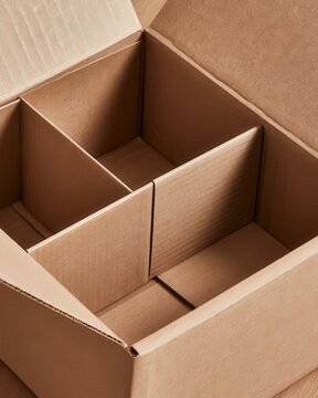Empty cardboard box with internal dividers on wooden floor