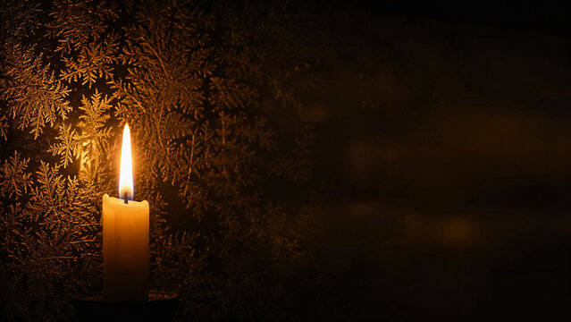 Single burning candle flame in front of frosted window with ice crystal pattern