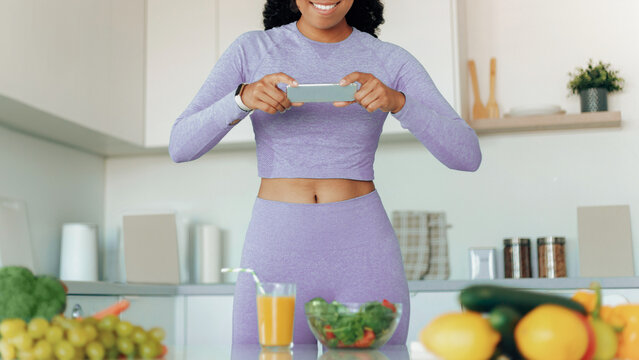 Smiling Black Female Fitness Enthusiast Taking A Photo Of A Healthy Meal With Fresh Ingredients In A Modern Kitchen. Showcasing Healthy Eating Lifestyle And Wellness Concept.