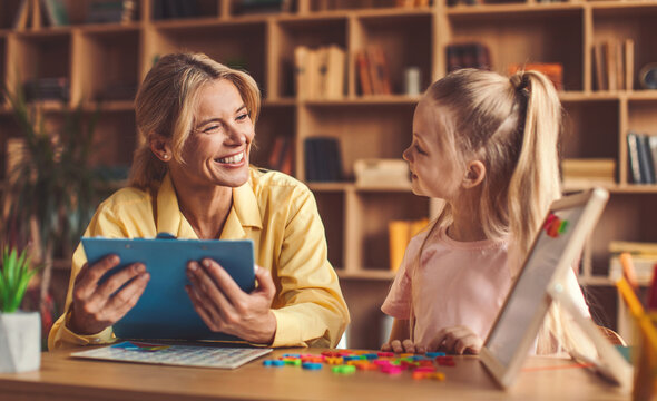 Smiling Caucasian Woman Teaching Young Girl In Office Setting, Engaged In Fun Learning Activities With Educational Materials, Creating A Positive Atmosphere For Growth And Development.