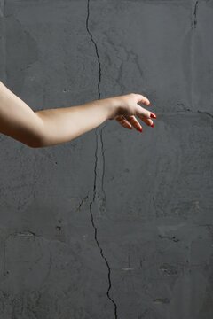Hand reaches out toward a gray wall in a simple indoor space