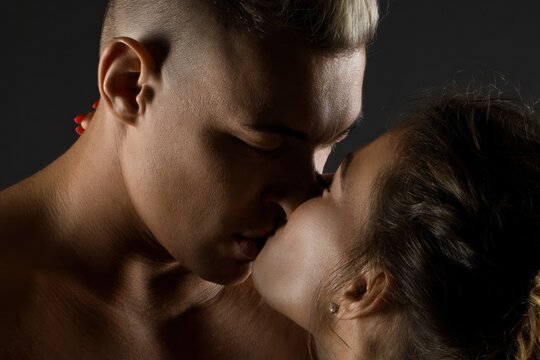Young attractive couple sharing a tender kiss in a close up studio shot