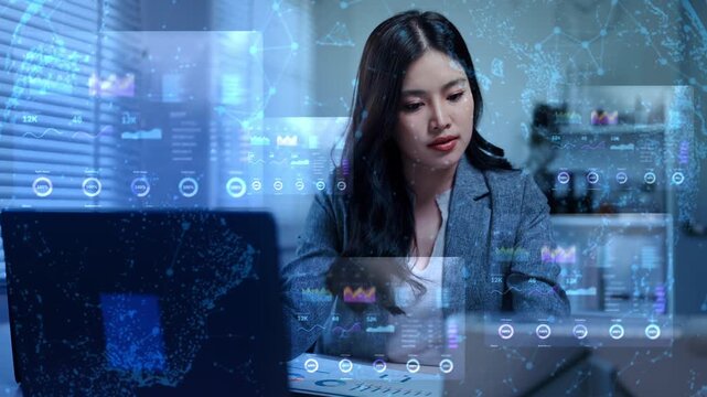 Asian businesswoman working late at night in an office, analyzing financial data and charts on glowing digital futuristic screens and graphs.
