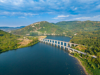 Obraz premium Bridge crossing river with green mountains in the background during daylight hours
