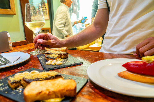Person enjoying wine glass with pinchos and tapas at bar