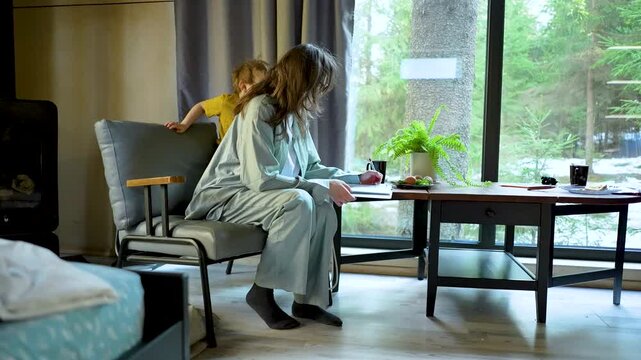 Mother sits in a cozy bedroom while her son stands behind, sharing tender moment during their peaceful evening routine. atmosphere captures a loving pause in their quiet home. happy family moments
